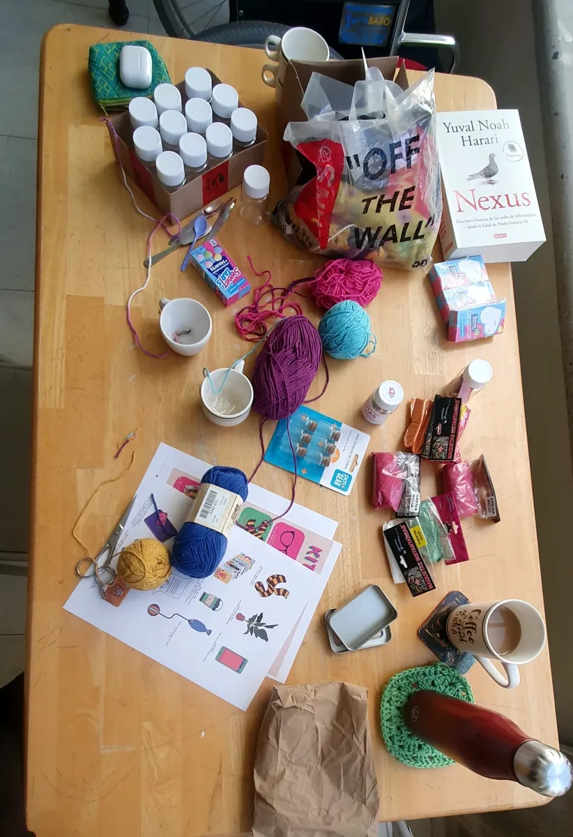 Mesa de trabajo con estambre, frascos, latas e impresiones del kit